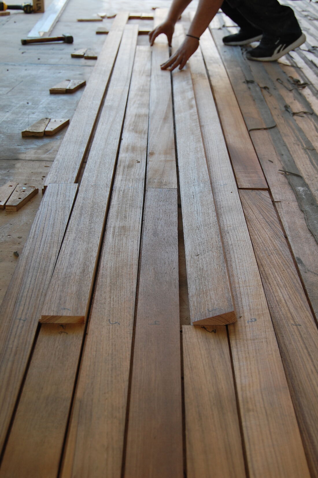 Hands laying numbered teak planks