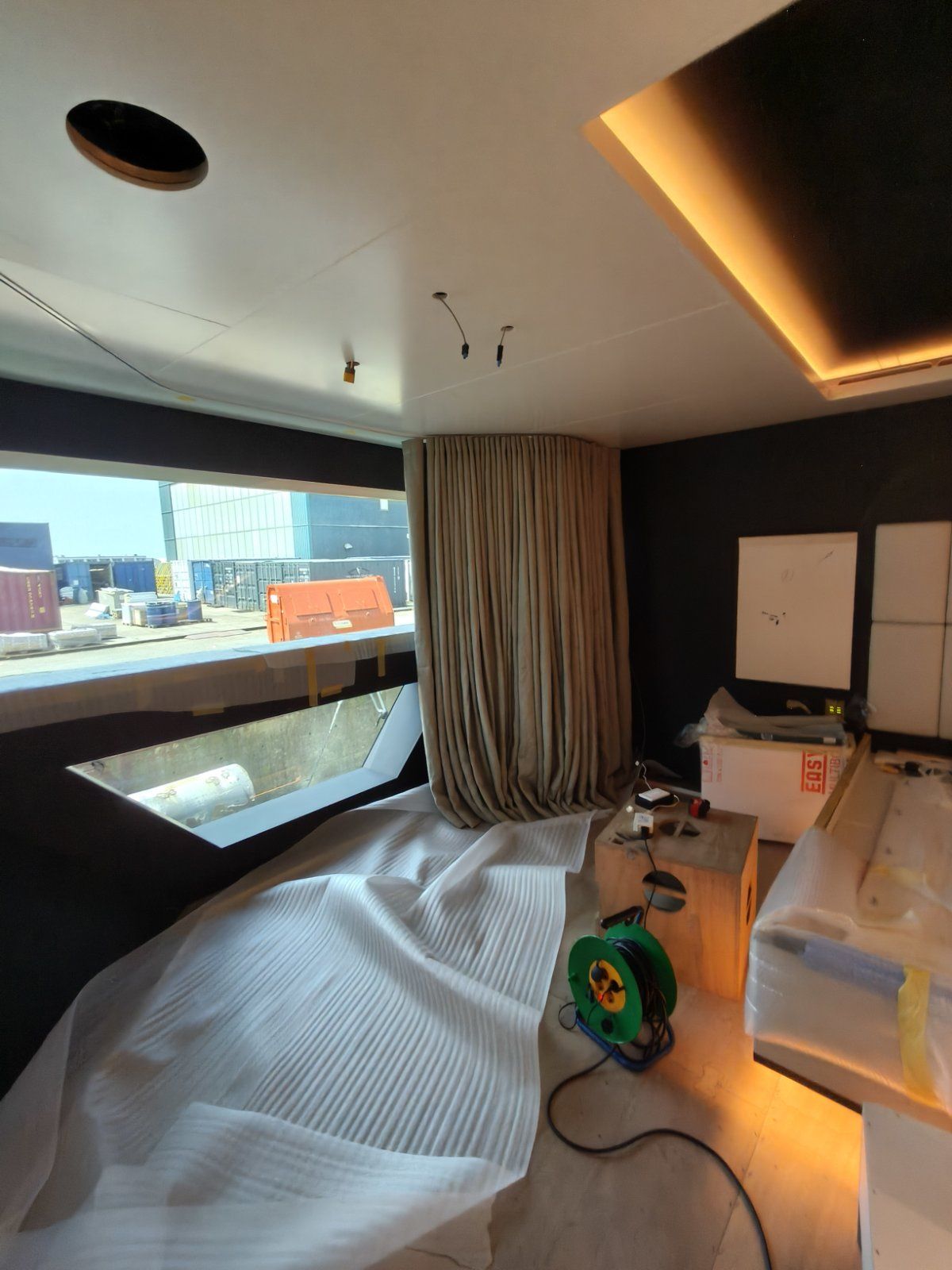 Curtain dressing during fit-out, shipyard visible through the window